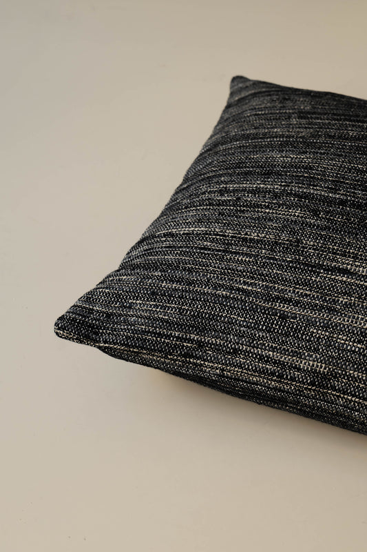 Gros plan sur l’angle du coussin Roquebrune – Ebano, mettant en valeur le tissu tissé à rayures et les coutures soigneusement finies