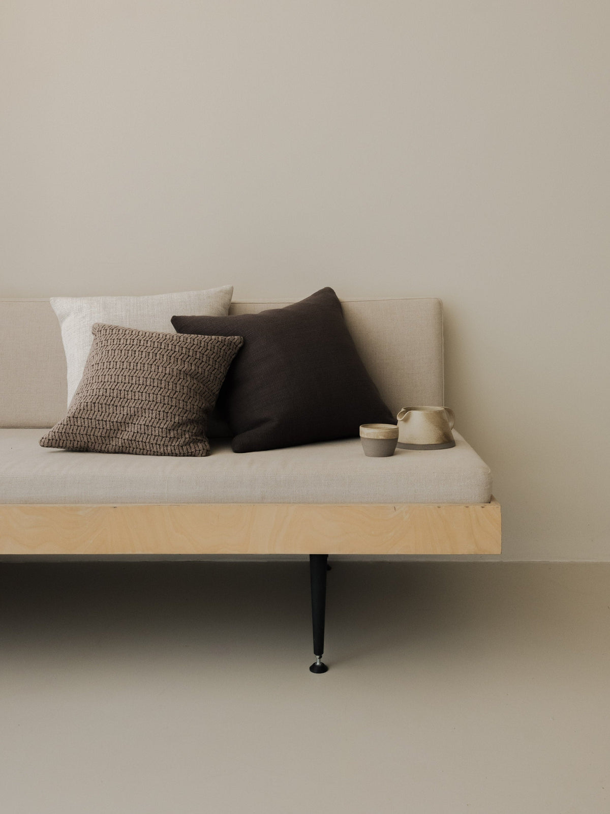Dark Detail – The Square Trio, featuring three textured cushions in deep neutral tones, styled on a white sofa with a wooden frame