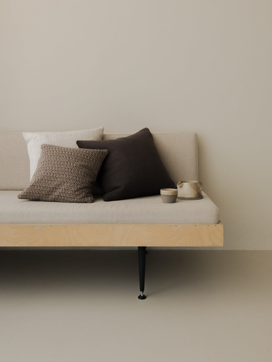 Dark Detail – The Square Trio, featuring three textured cushions in deep neutral tones, styled on a white sofa with a wooden frame