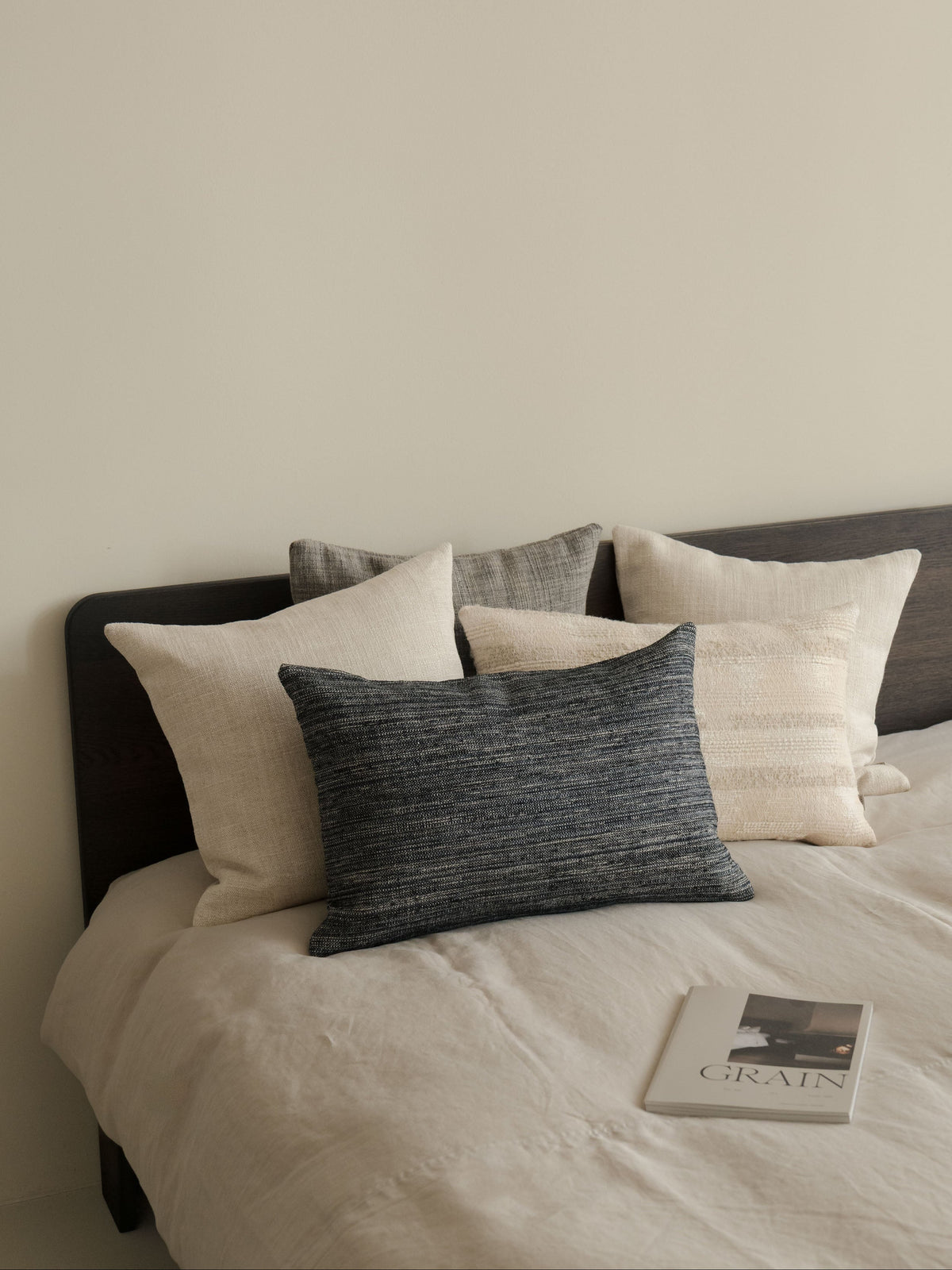 Hints of Blue – a set of five decorative cushions in natural, brown and muted blue tones, styled on a bed