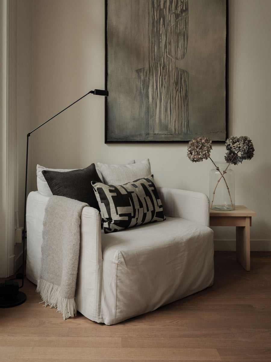 Warm Contrast – The Asymmetric Trio, featuring three cushions in warm neutral tones with contrasting textures, styled on a white armchair