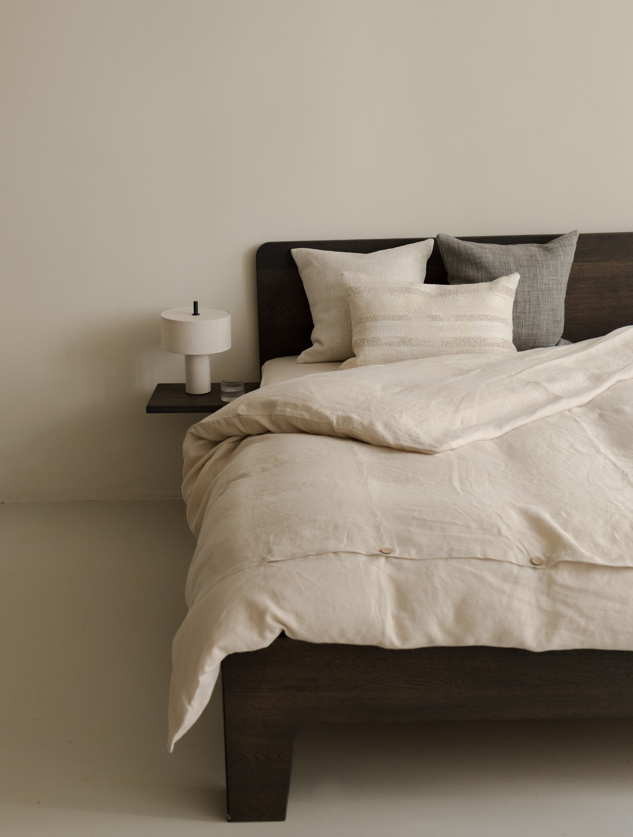 Hints of Blue – Noricum cushion set in natural, brown and muted blue-grey tones, styled on a bed