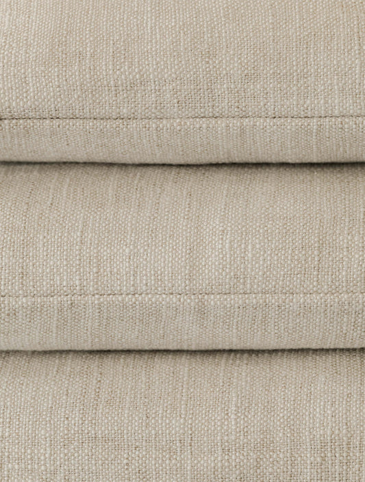 Close-up of a stack of three Mélange Moderne – Calcare cushions, highlighting the soft woven texture and subtle tonal variation