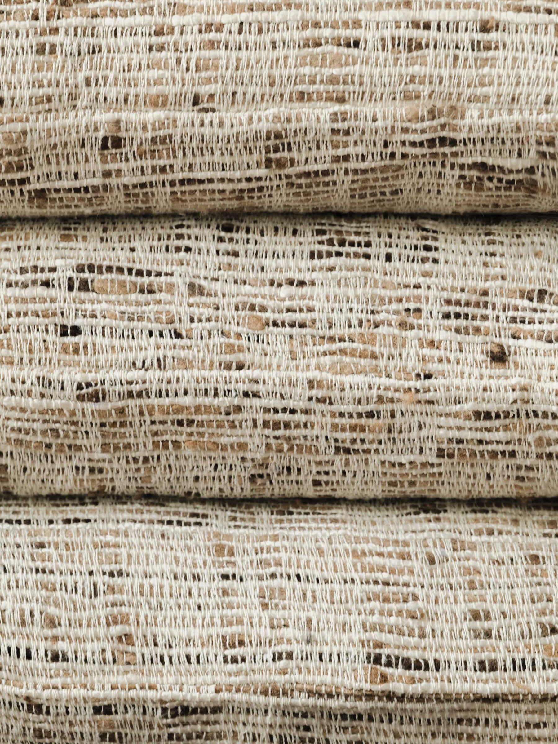 Gros plan sur une pile de coussins Nicomaco – Raw, mettant en valeur la surface sculpturale et la texture en couches