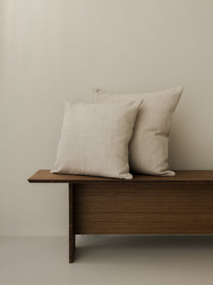 Paradou – Dune cushions in 50 × 50 cm and 60 × 60 cm, displayed together on a dark wooden bench