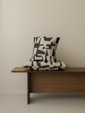 Pazl – Shadow cushions in 40 × 40 cm and 60 × 40 cm, displayed together on a dark wooden bench
