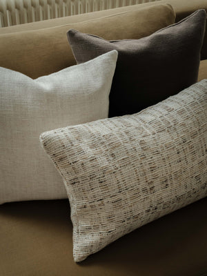 Close-up of the Raw Tones – The Asymmetric Trio, highlighting the cushions’ warm neutral shades and contrasting woven textures