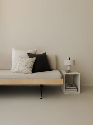 Raw Tones – The Square Trio, featuring three textured cushions in warm neutral shades, styled on a white sofa with a wooden frame