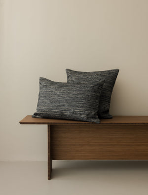 Roquebrune – Ebano cushions in 50 × 50 cm and 60 × 40 cm, displayed together on a dark wooden bench