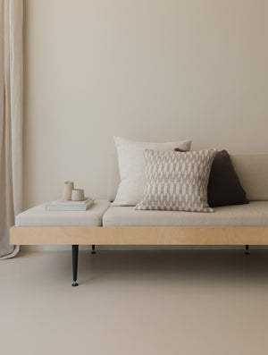 Shifting Shades – The Square Trio, featuring three textured cushions in layered neutral tones, styled on a white sofa with a wooden frame